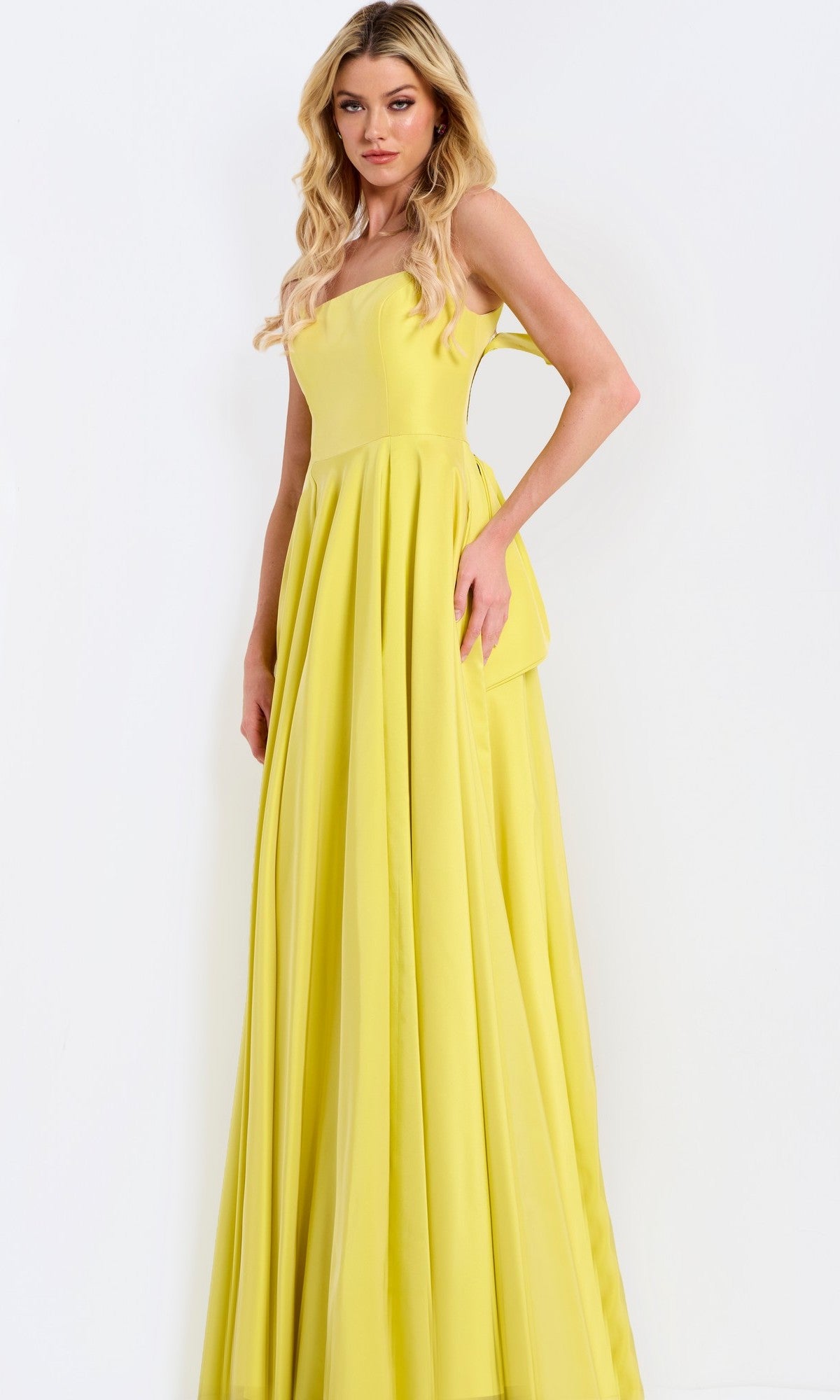A woman wears the Jovani 47496 long prom dress featuring a bright yellow sleeveless fitted bodice and an a-line, flowy pleated skirt, standing against a plain white background.